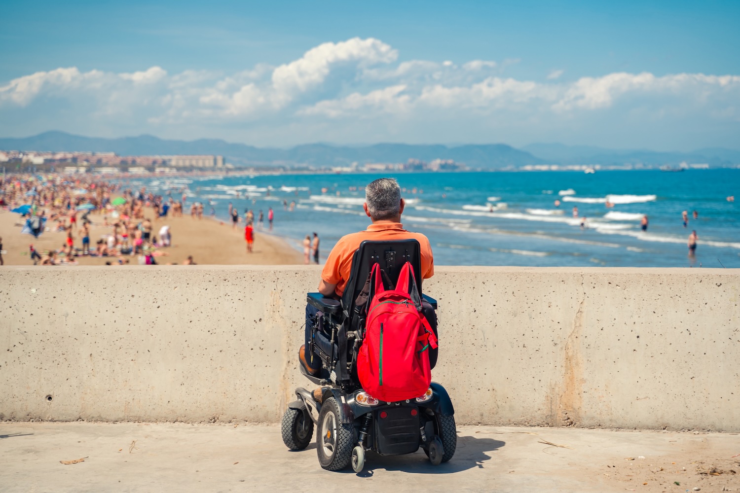 Man who uses motorized wheelchair views a beach abroad.